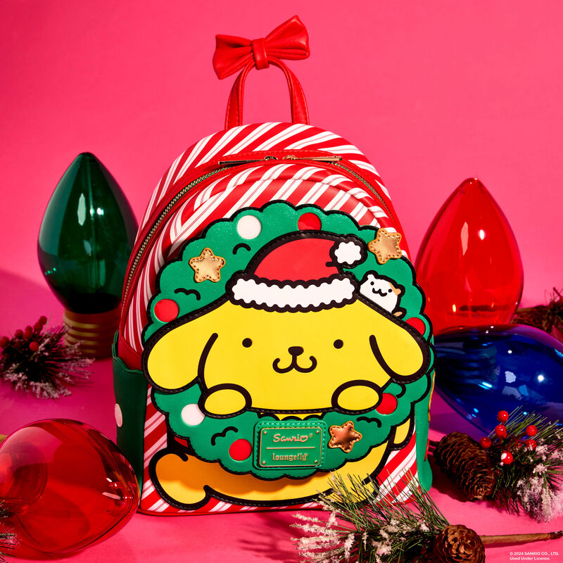 Red and white mini backpack featuring Pompompurin popping out through a wreath on the front. The bag sits against a light red background and is surrounded by large holiday lights