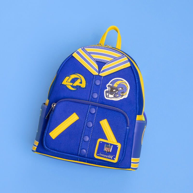 Blue and yellow Loungefly mini backpack featuring a Los Angeles Rams varsity jacket on the front. The bag sits against a light blue background. 