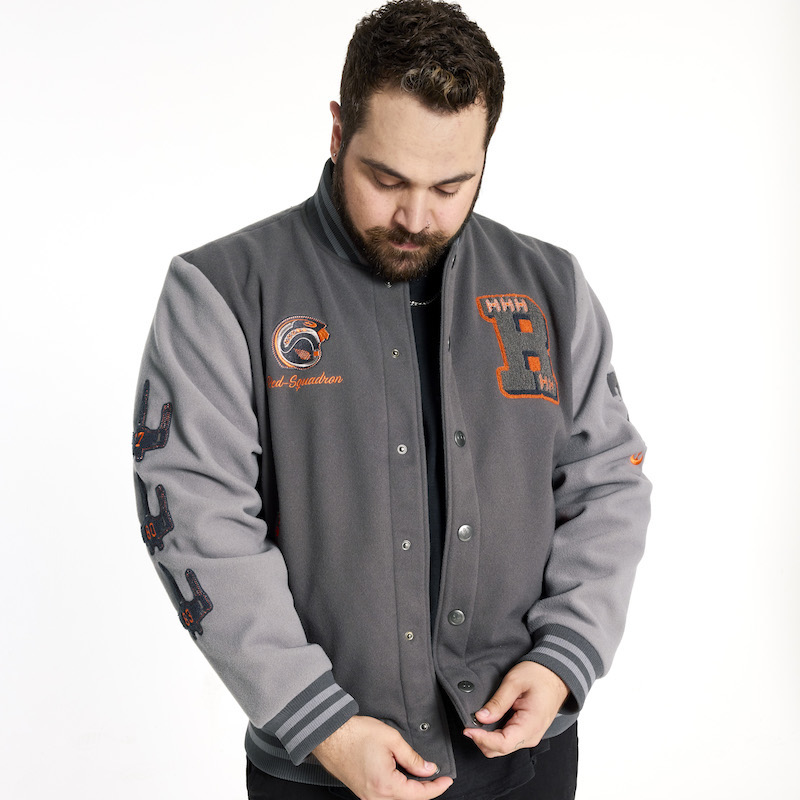 Man with beard wearing the grey Loungefly COLLECTIV Star Wars Rebel Alliance VRSITY Jacket and standing against a white background