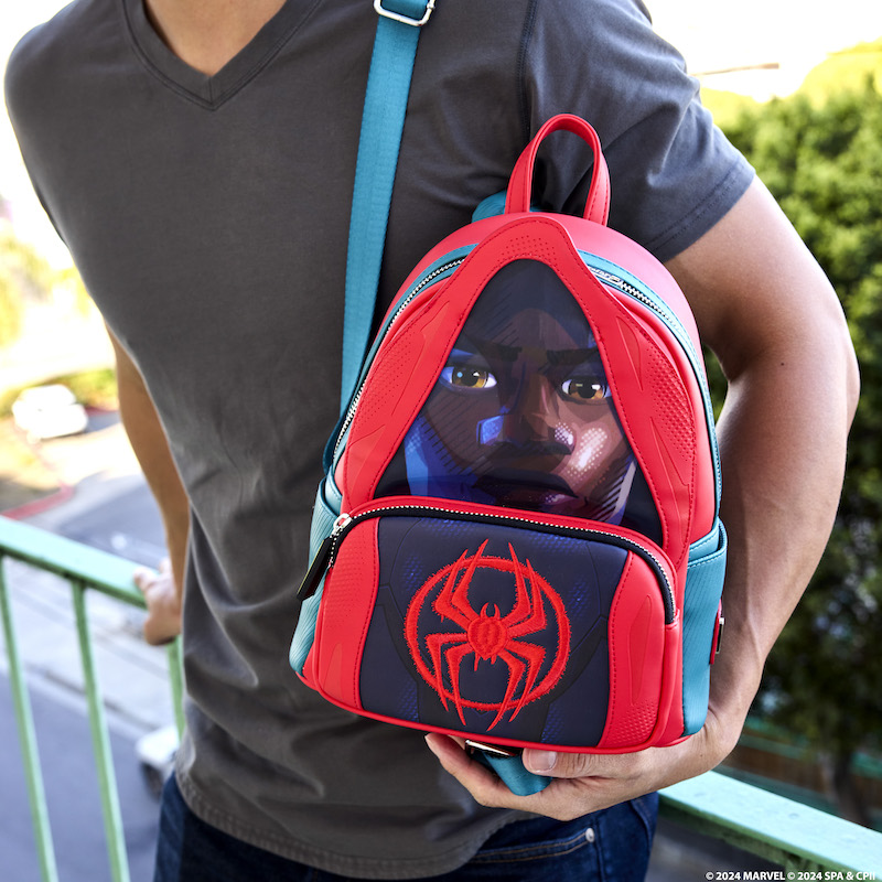 Man leaning against a fire escape raining holding the Loungefly Spider-Verse Miles Morales Hoodie Lenticular Mini Backpack, featuring Miles wearing a hoodie over his Spider-Man suit, with a lenticular panel that switches between Miles' face and his mask