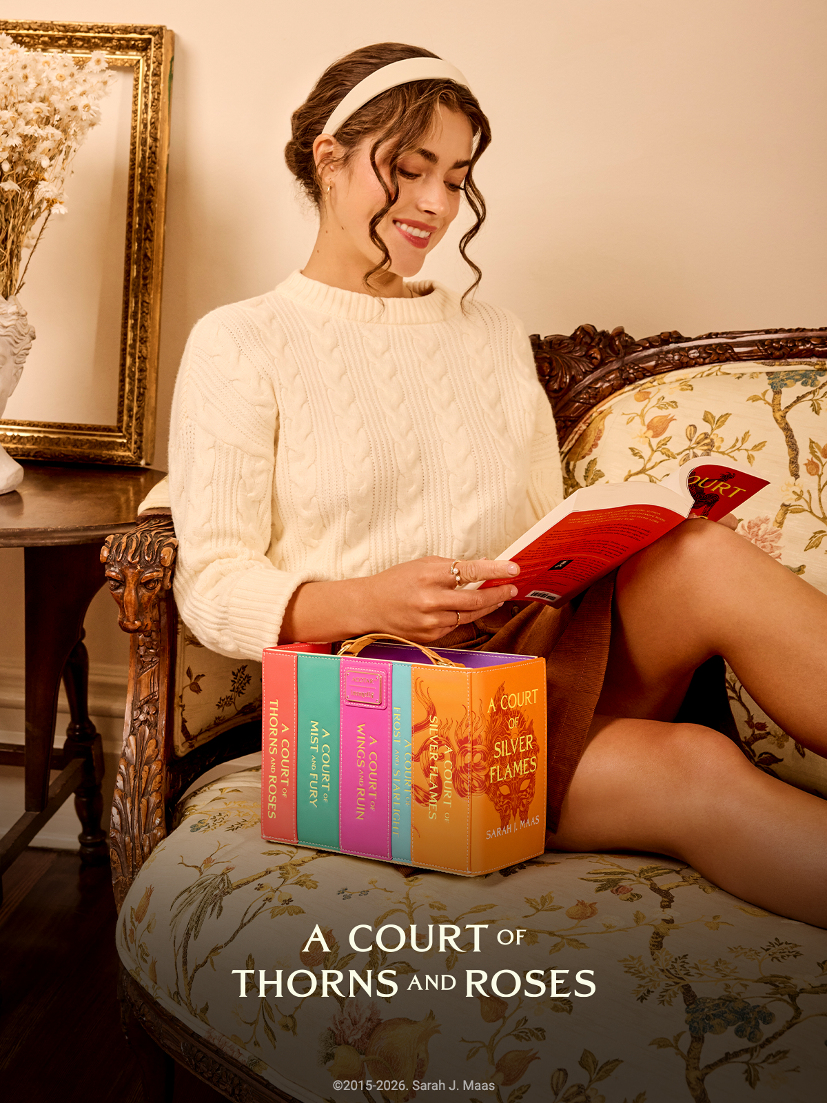 Woman reading book on sofa seat featuring Loungefly A Court of Thorns & Roses Books Crossbody Bag
