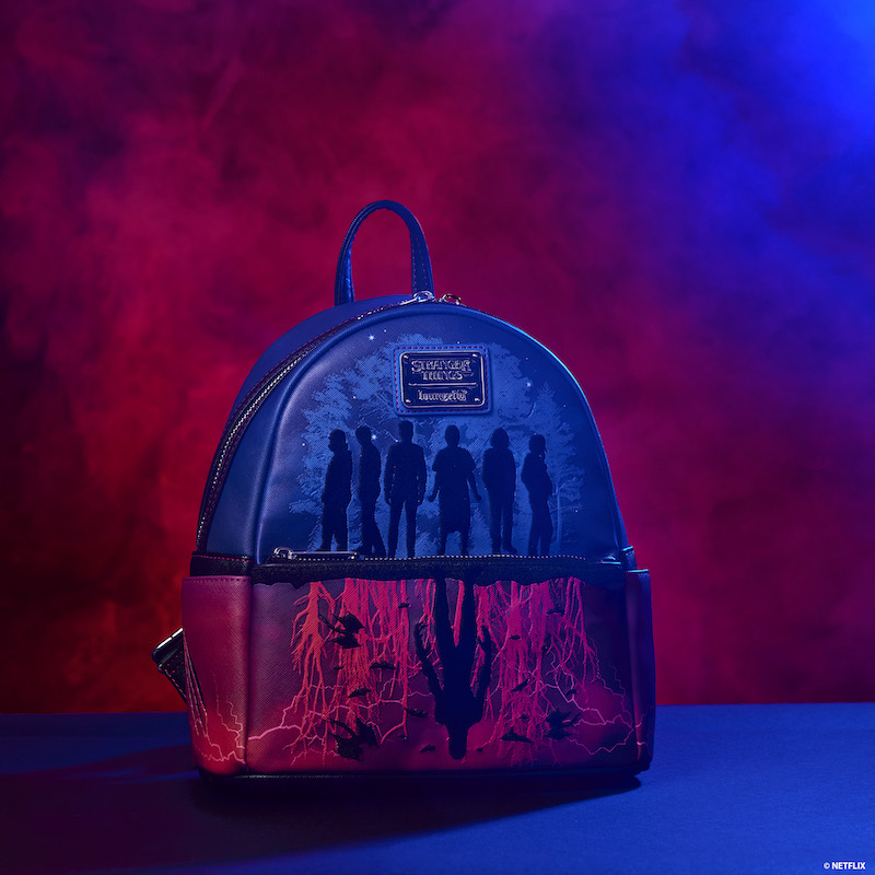 Red and blue Stranger Things mini backpack sitting on a blue surface against a dark red background 
