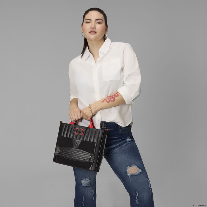 Woman wearing a white top and ripped jeans, holding the Loungefly STAR WARS&trade; Darth Maul convertible backpack and tote bag by the top handles. She stands against a grey background. 