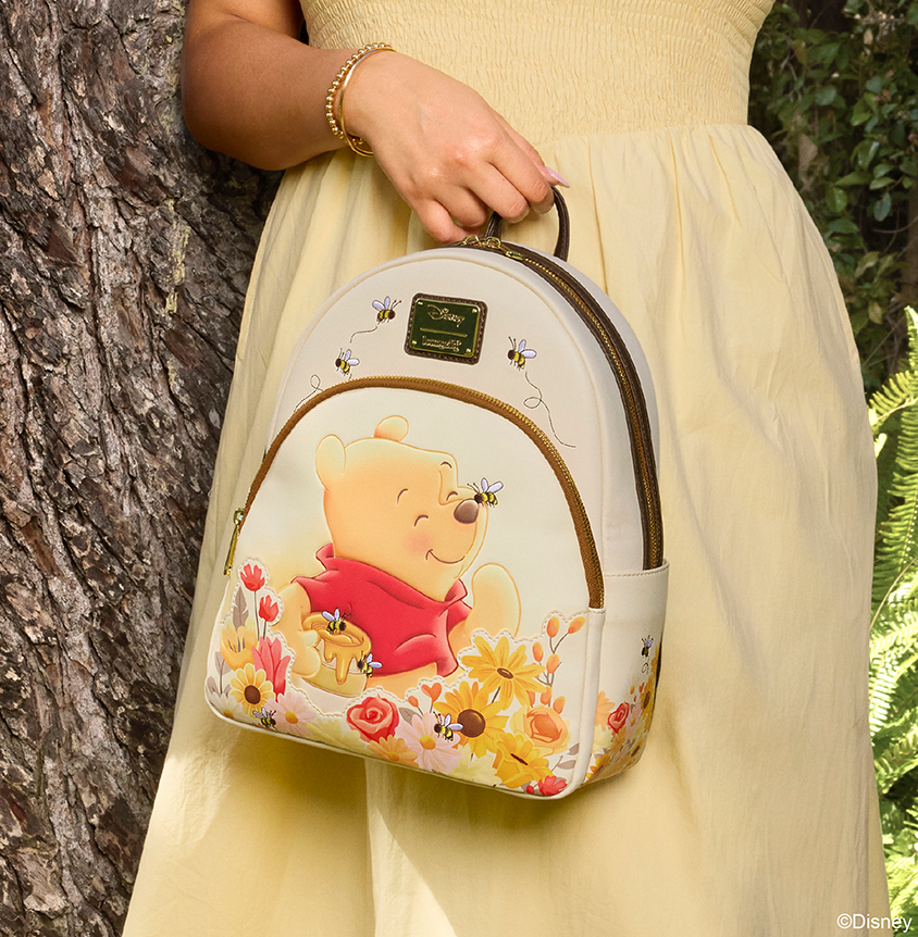 Girl with Yellow dress showing Loungefly Disney Winnie the Pooh mini backpack