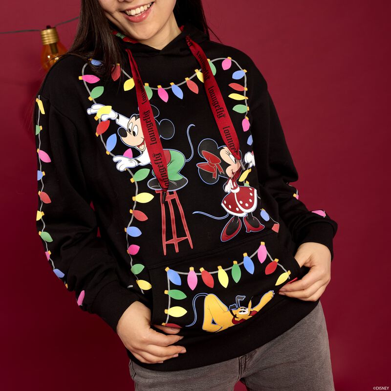 Woman standing against a dark red background wearing the Loungefly Mickey & Friends Holiday String Lights hoodie. 