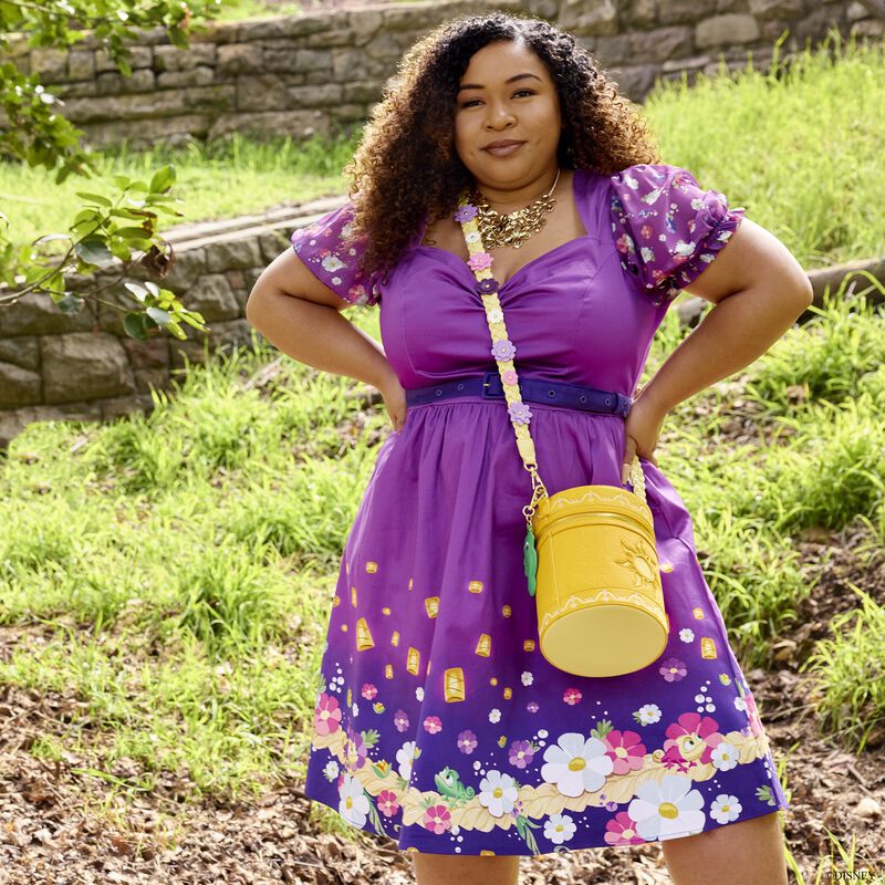 Woman outside wearing a purple Stitch Shoppe Rapunzel Dress with the Rapunzel Lantern Glow Crossbody Bag