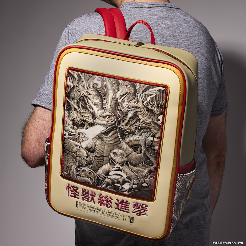 Man facing away from camera wearing a grey shirt and wearing the Loungefly NYCC Exclusive Limited Edition Godzilla bag, featuring Mondo artwork. The bag also makes Godzilla sounds. 