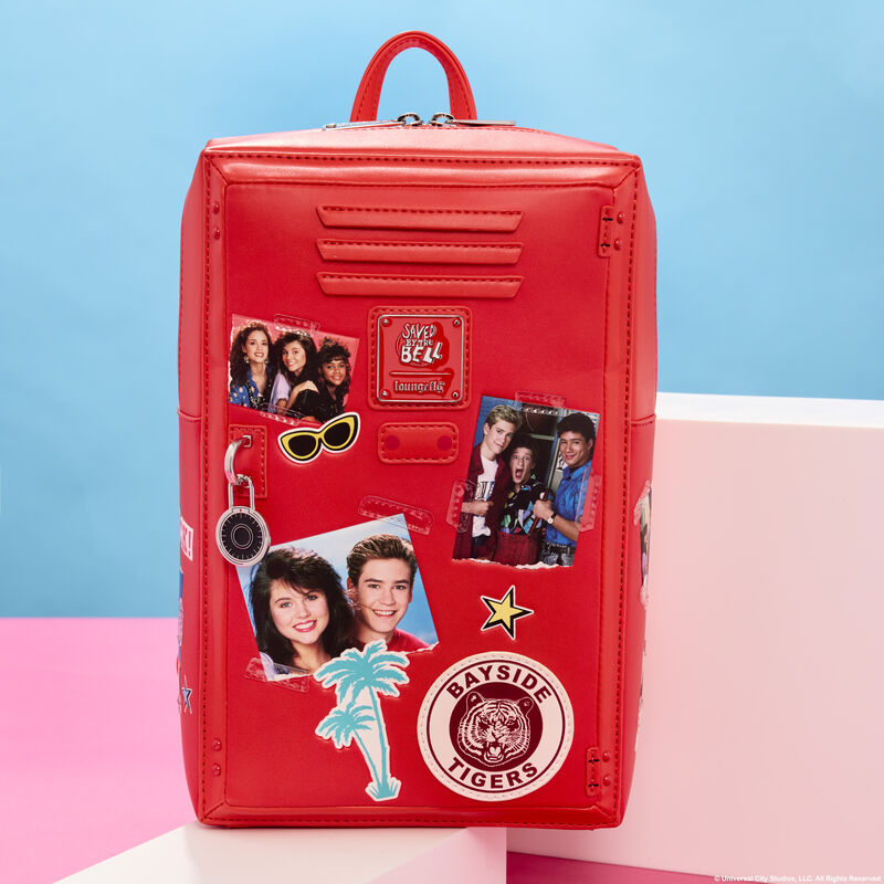 Rectangular, red Loungefly Saved by the Bell mini backpack that looks like a high school locker with pictures from Saved by the Bell on it. The bag sits on two white cubes against a blue and pink background. 