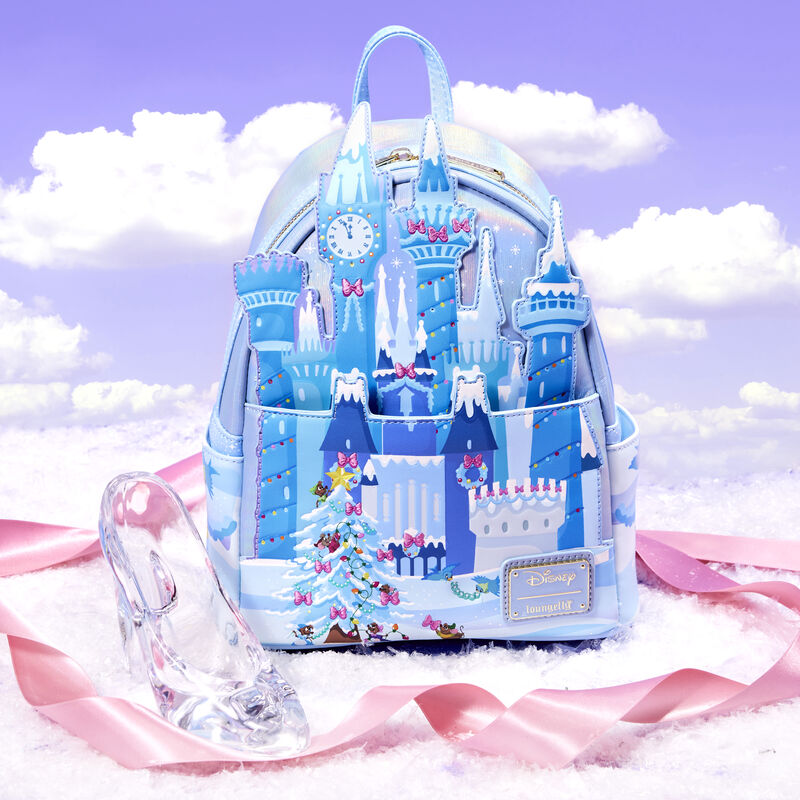 Image of our Cinderella Exclusive Holiday Castle Light Up Mini Backpack against a purple background with clouds and surrounded by a pink satin ribbon and glass slipper 
