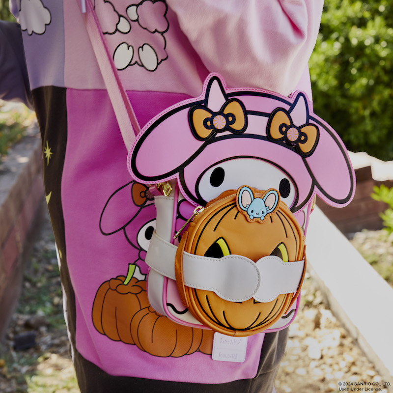 Woman standing outside wearing the Hello Kitty and Friends Costume Unisex Hoodie and wearing the My Melody Pumpkin Crossbuddies bag, featuring My Melody holding a pumpkin coin pouch. 