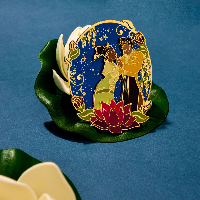 3-inch limited edition Loungefly pin featuring Princess Tiana and Prince Naveen dancing, surrounded by flowers and a starry night sky. The pin sits on a leaf against a dark blue background. 